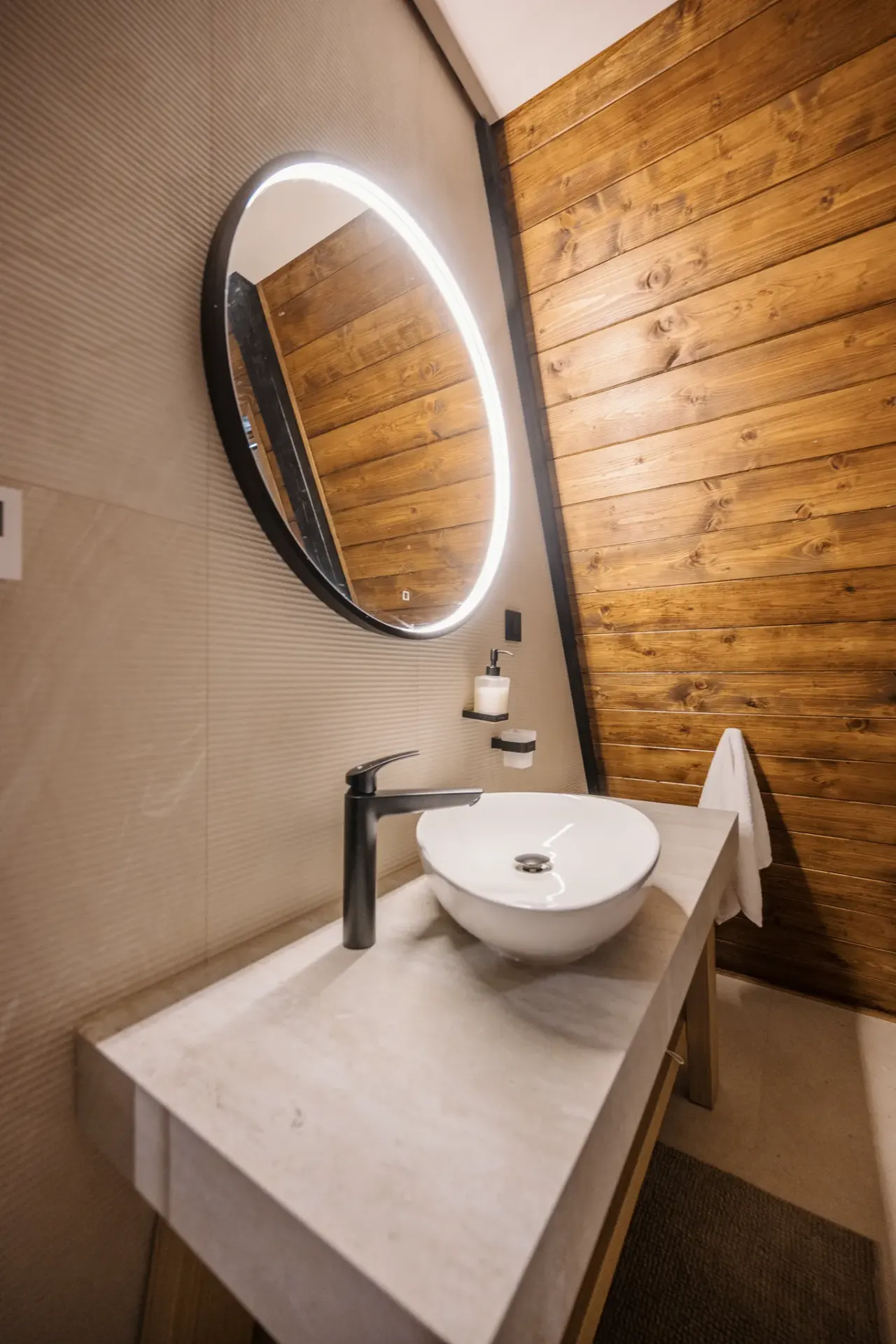 Ensuite bathroom with a round backlit mirror and stone vessel basin