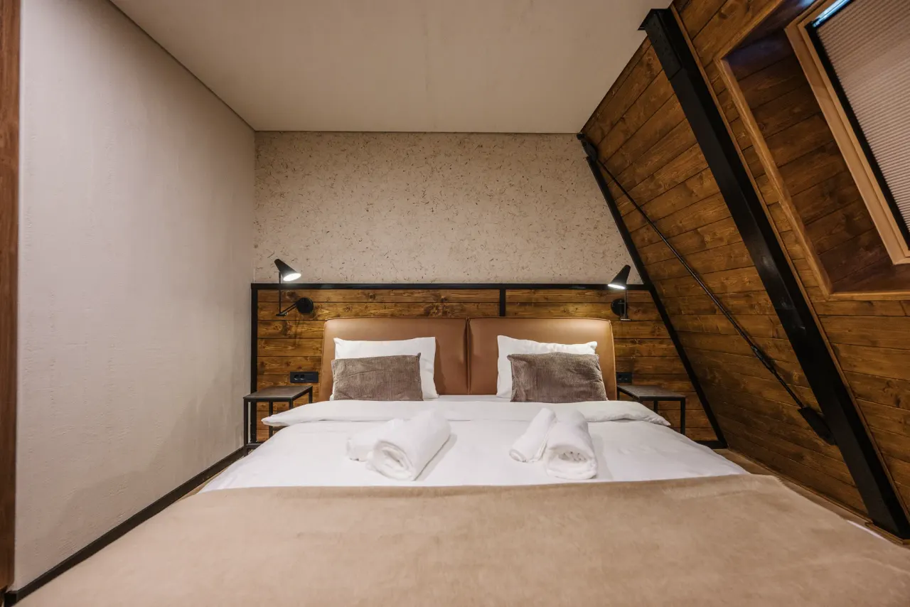 Cognac leather bed against a timber headboard wall with reading lights and bedside tables