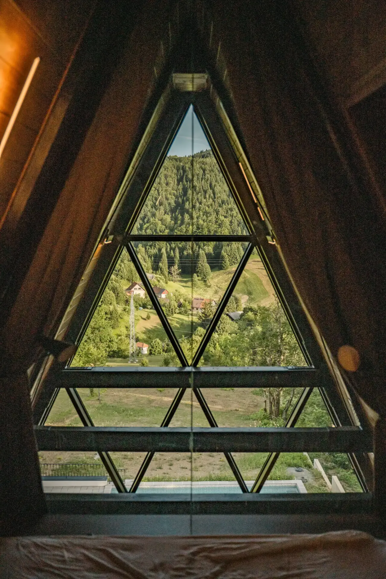 The triangular gable window framing the Gorski kotar forest from the peak bedroom