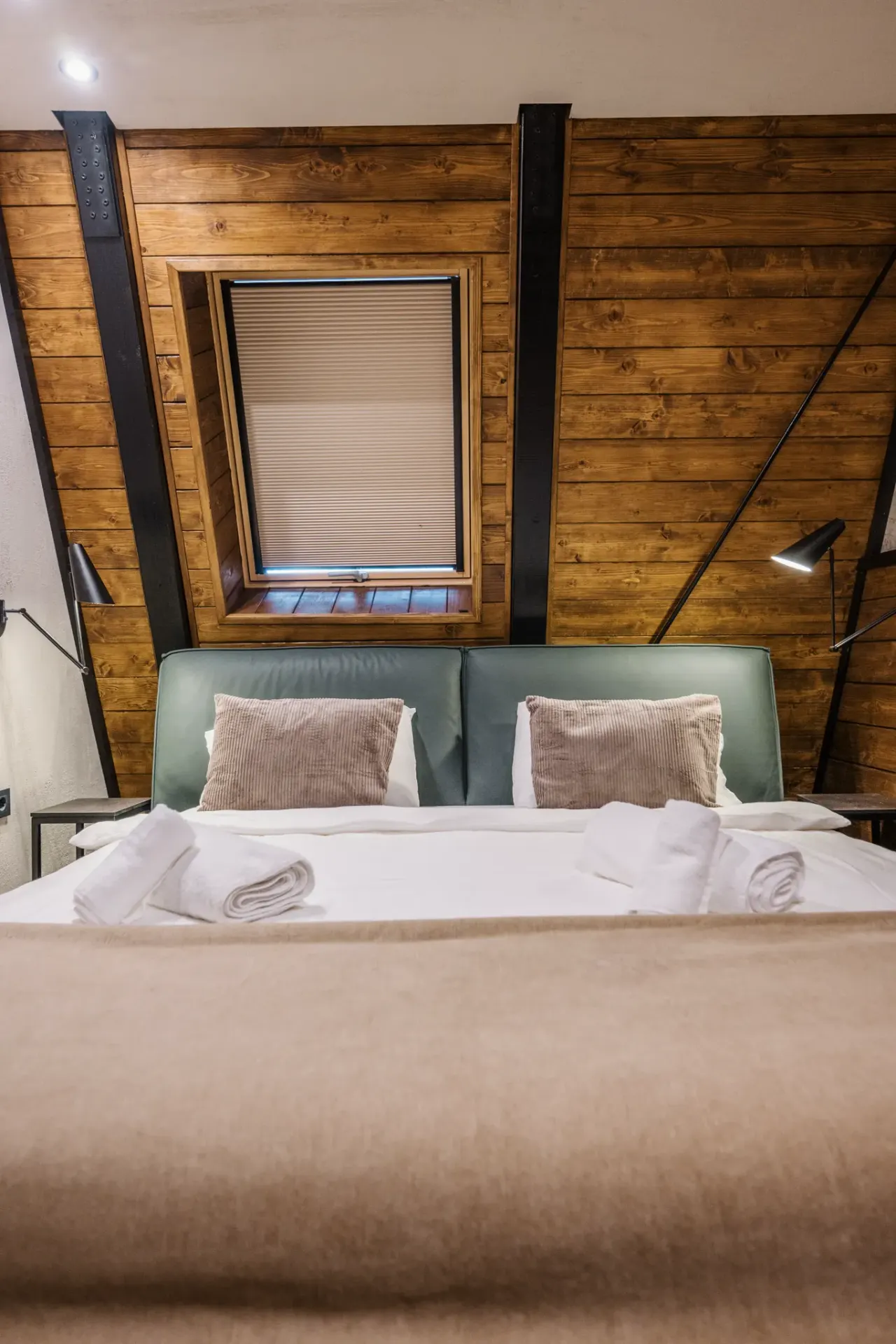 Bedroom with a sage-green upholstered headboard beneath the timber slope