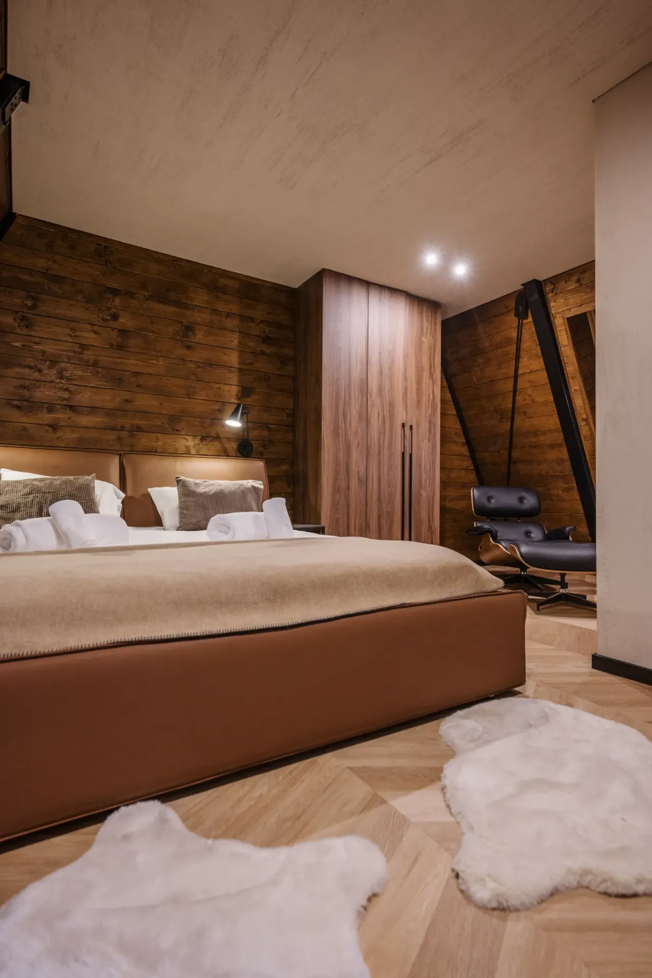 Bedroom with a cognac leather bed, lounge chair and sheepskin rugs