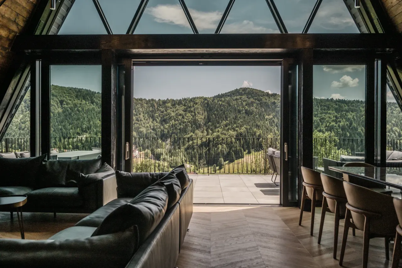 Living room glass wall slid open to the terrace and forested valley