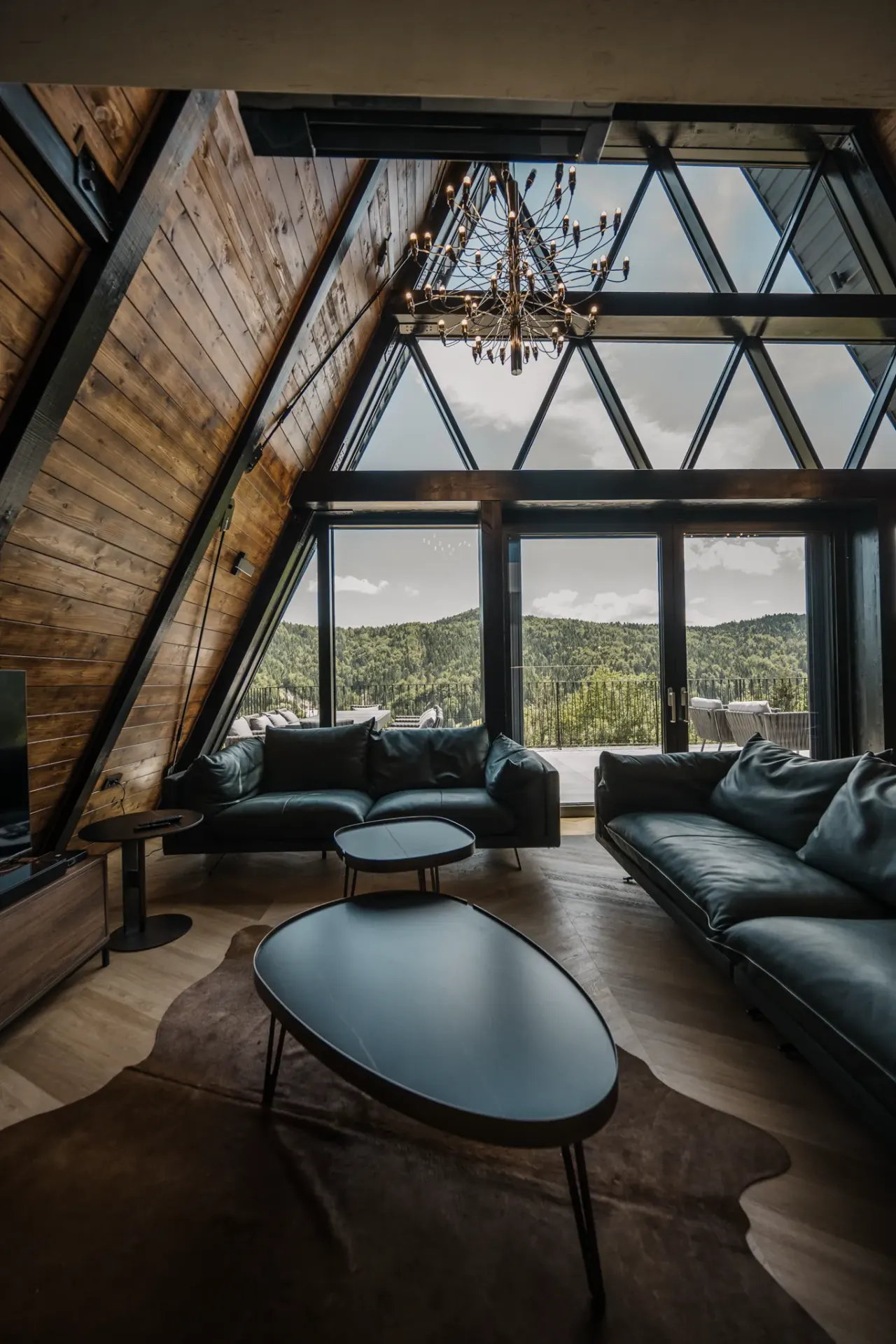 Leather sofas and a low table beneath the double-height glass gable