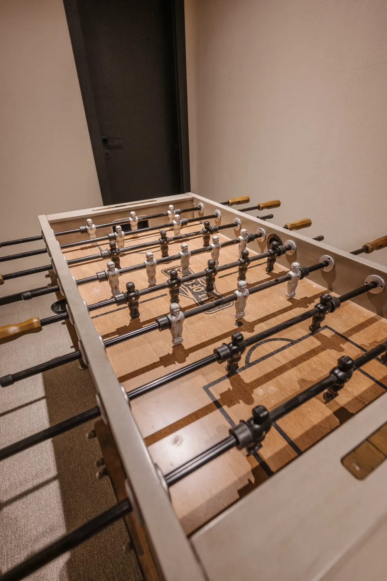 The foosball table seen from above, timber handles along the playing field