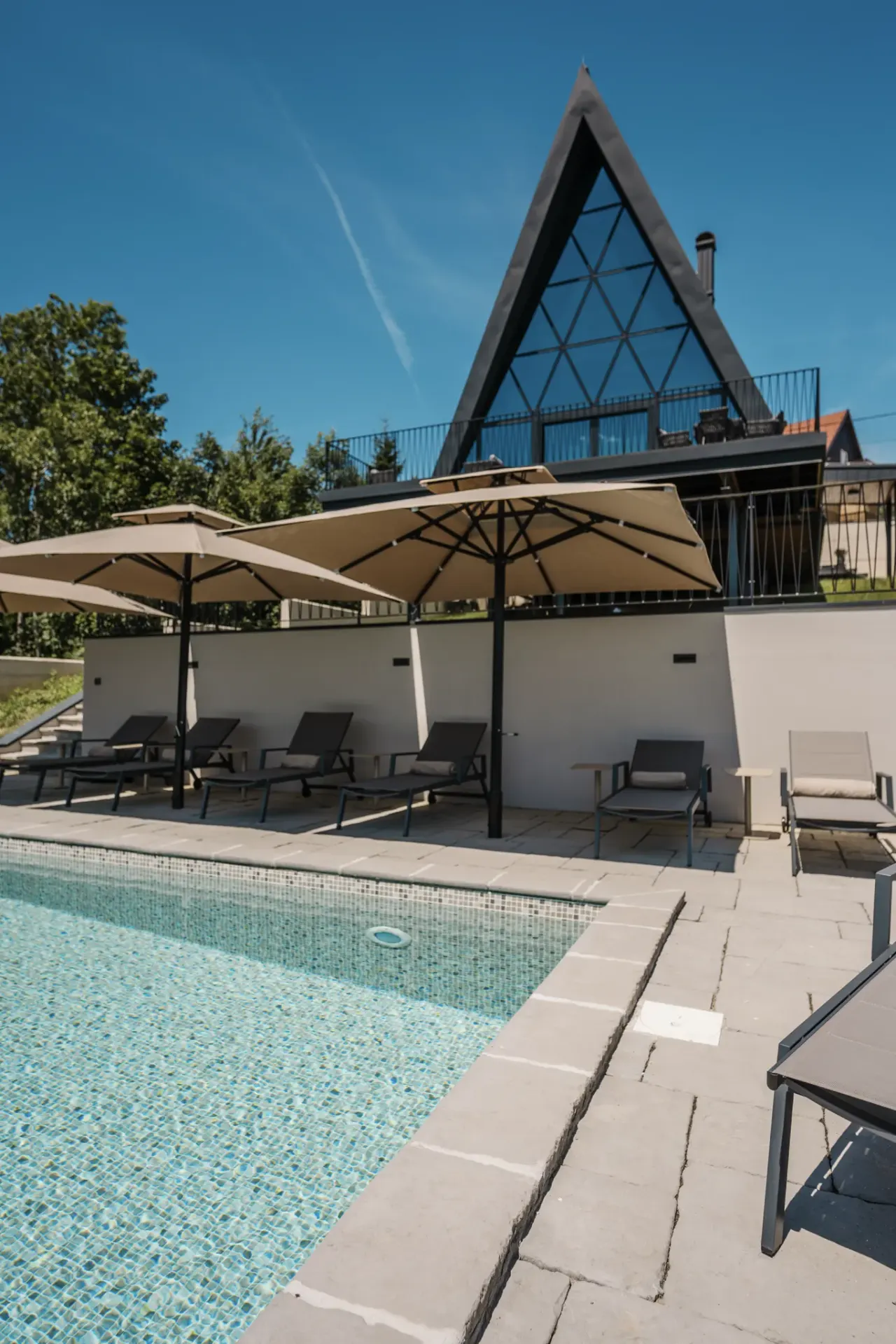 Poolside loungers and parasols with the A-frame beyond