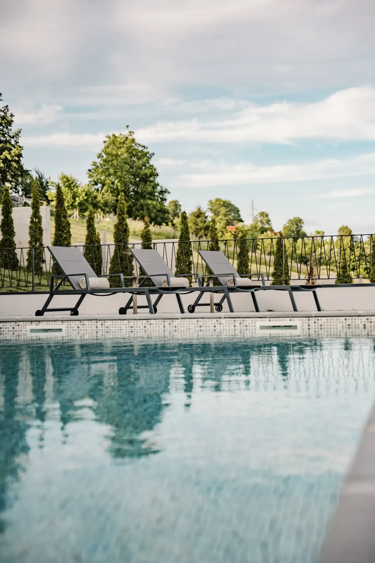 The 50 m² heated pool with sun loungers along a clipped cypress hedge