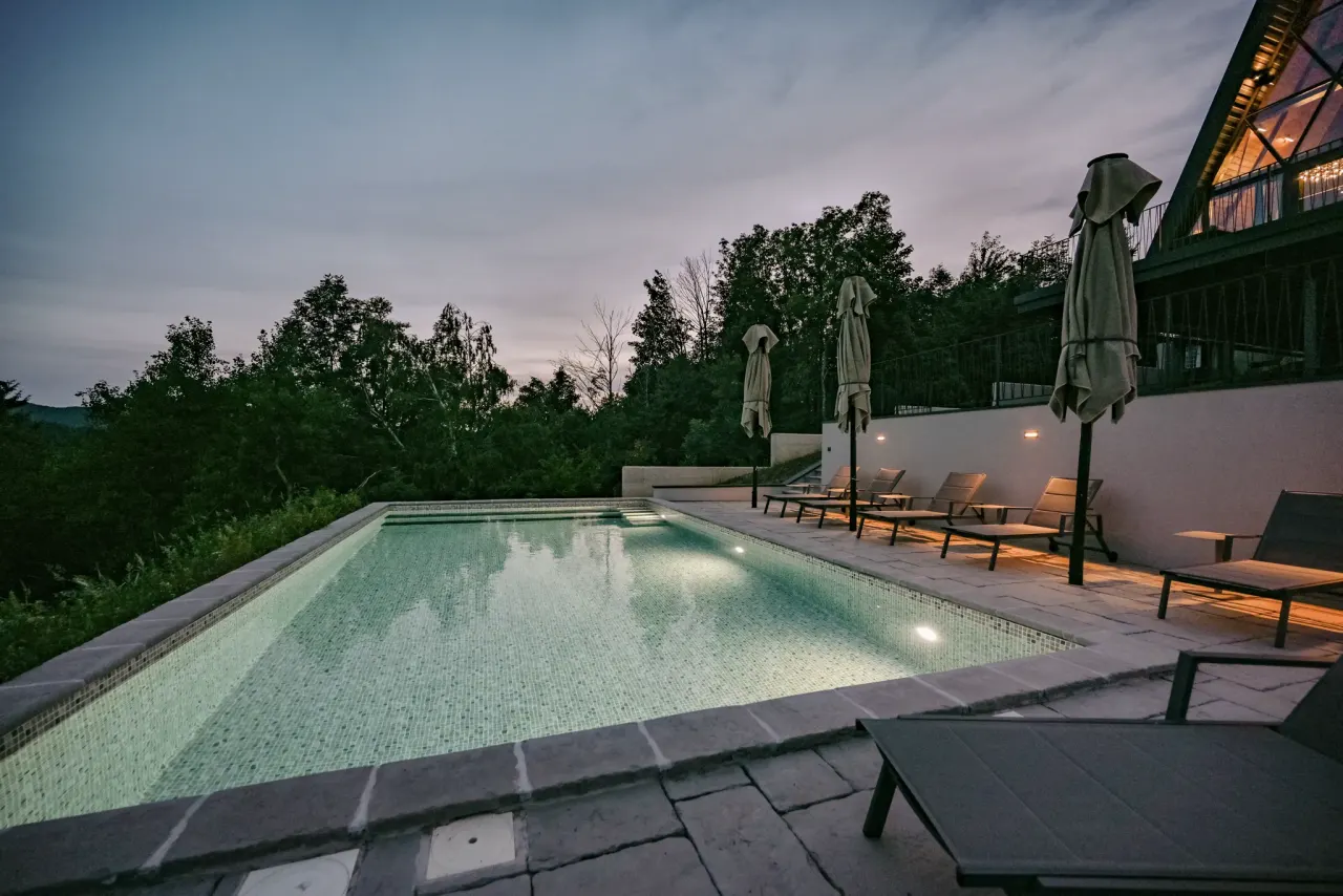 The pool glowing through the blue hour with the terrace lights coming on