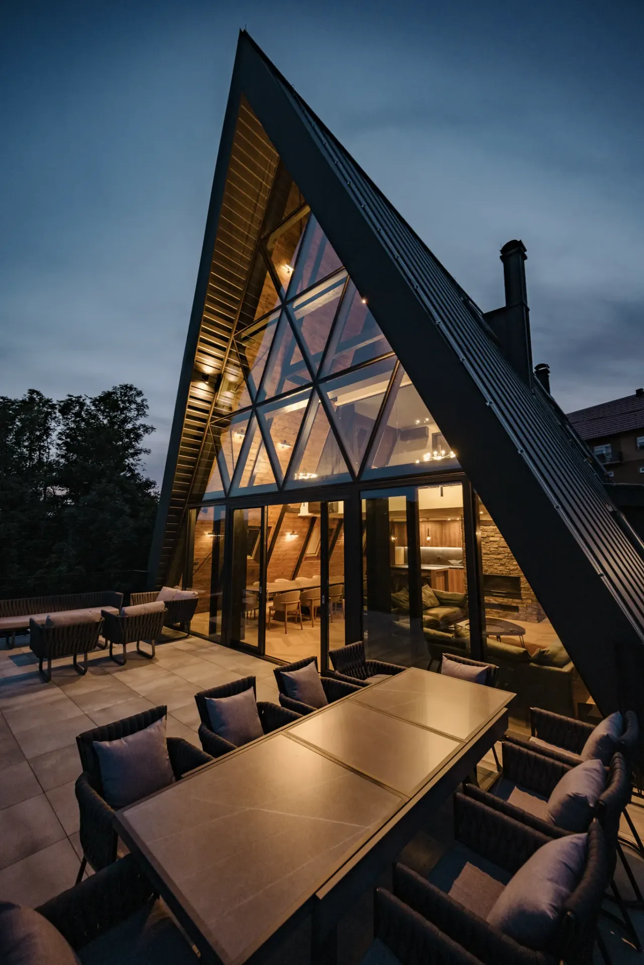 The black A-frame villa at dusk with its terrace dining table