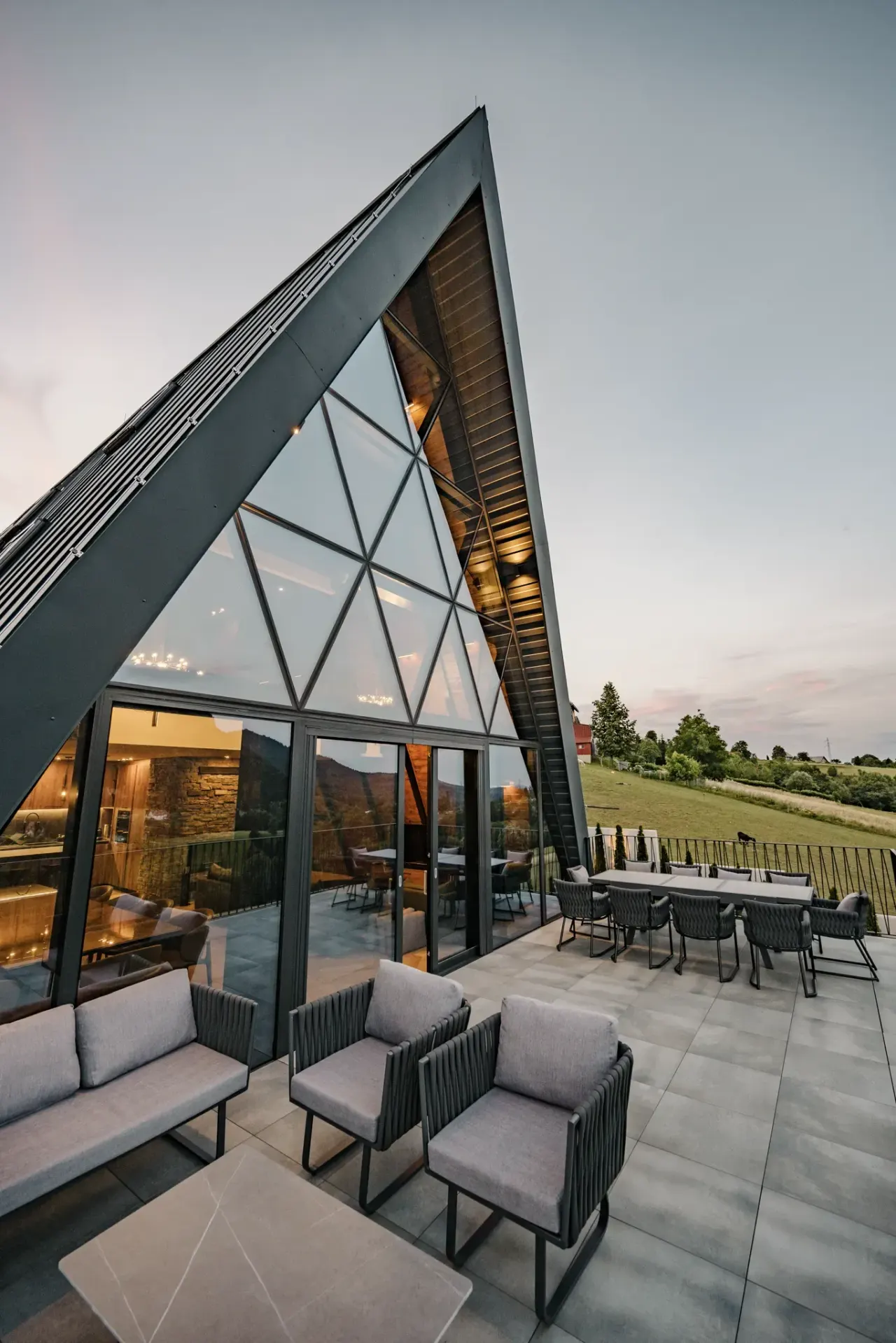 The lit A-frame gable above the terrace as evening settles over Gorski kotar