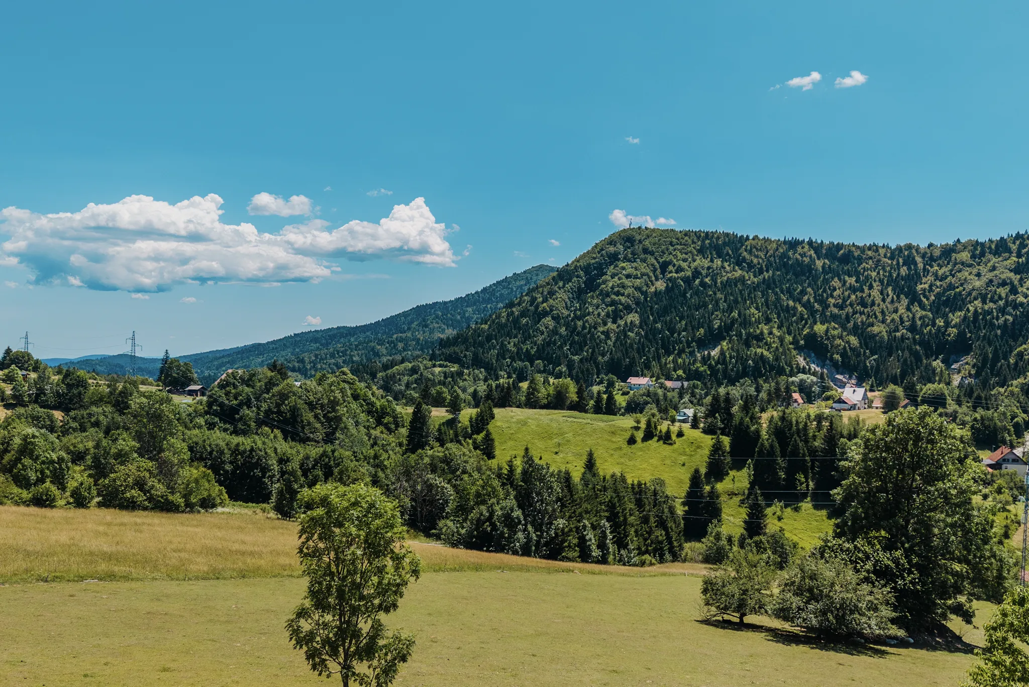 Aerial over the forested ridge of Ravna Gora in Gorski kotar, treetops stretching to the horizon with The Frame on the highest part